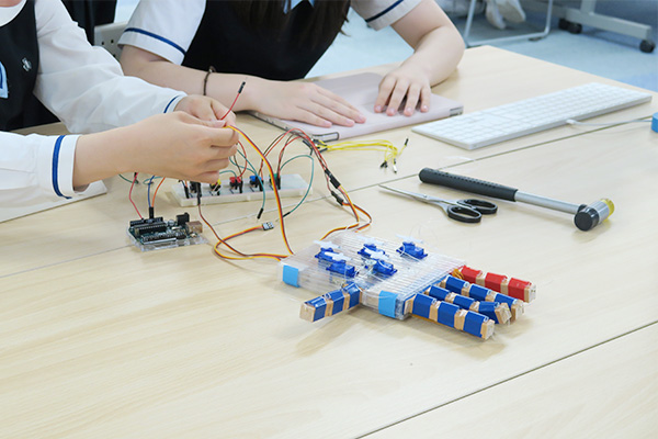 木片ブロックで制作した手にコードをつなげている写真