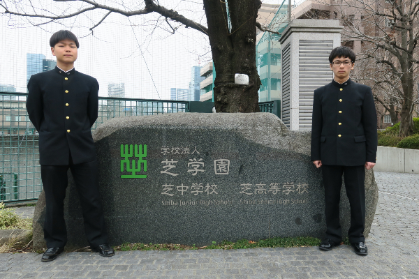 芝中学校 芝高等学校の校名碑の横に立つ田邊さんと冨田さんの写真